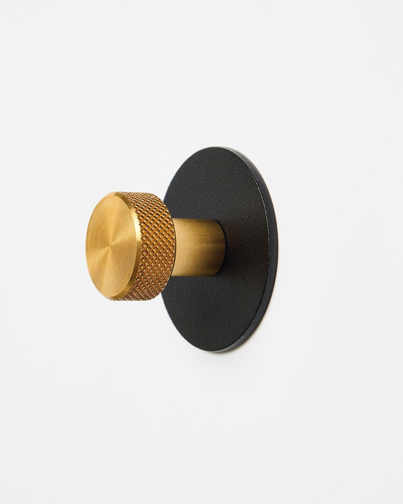 Gancio appendiabiti Norr X1 di WoodUpp con pomello brass testurizzato e base black in steel verniciato a polvere, accessorio per Akupanel, presentato su sfondo bianco.