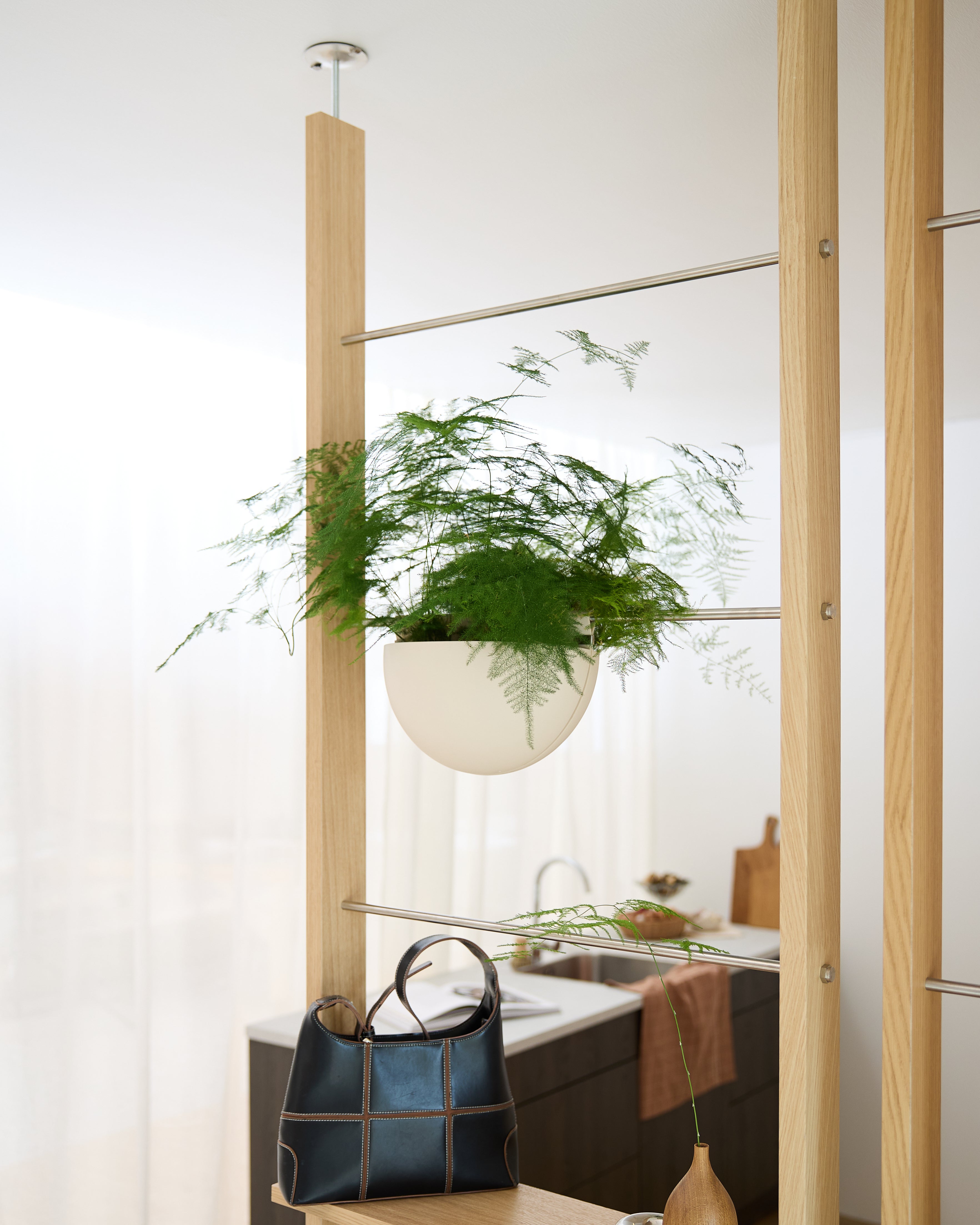 Una tasca Gro Soft (4L) di WoodUpp è fissata a una struttura in legno sopra una borsa nera in una cucina luminosa e moderna.