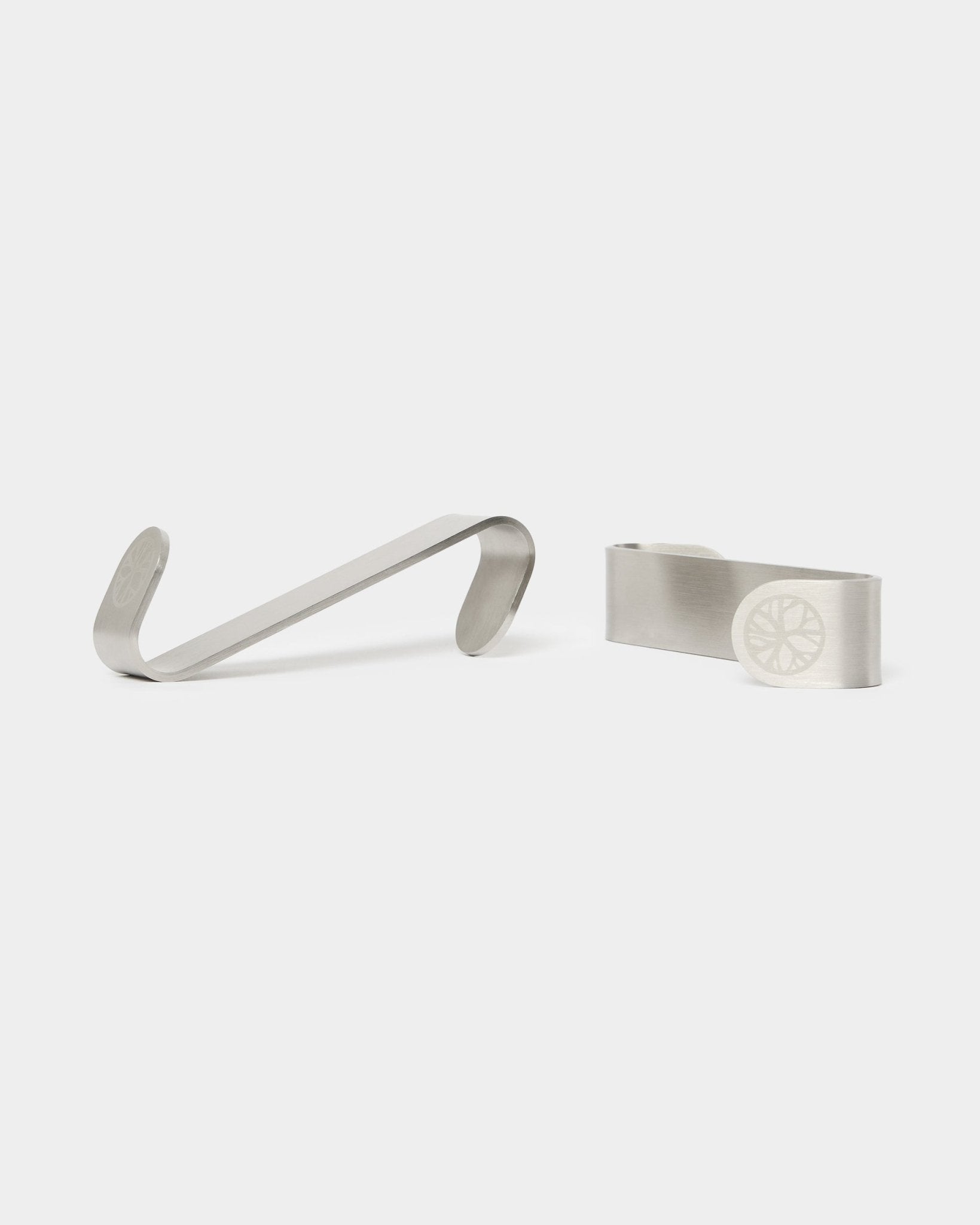WoodUpp Alva S-Hook BM1 e fermasoldi BM2, due accessori in steel inox con design inciso a ruota, progettati per pannelli acustici nordici in legno.