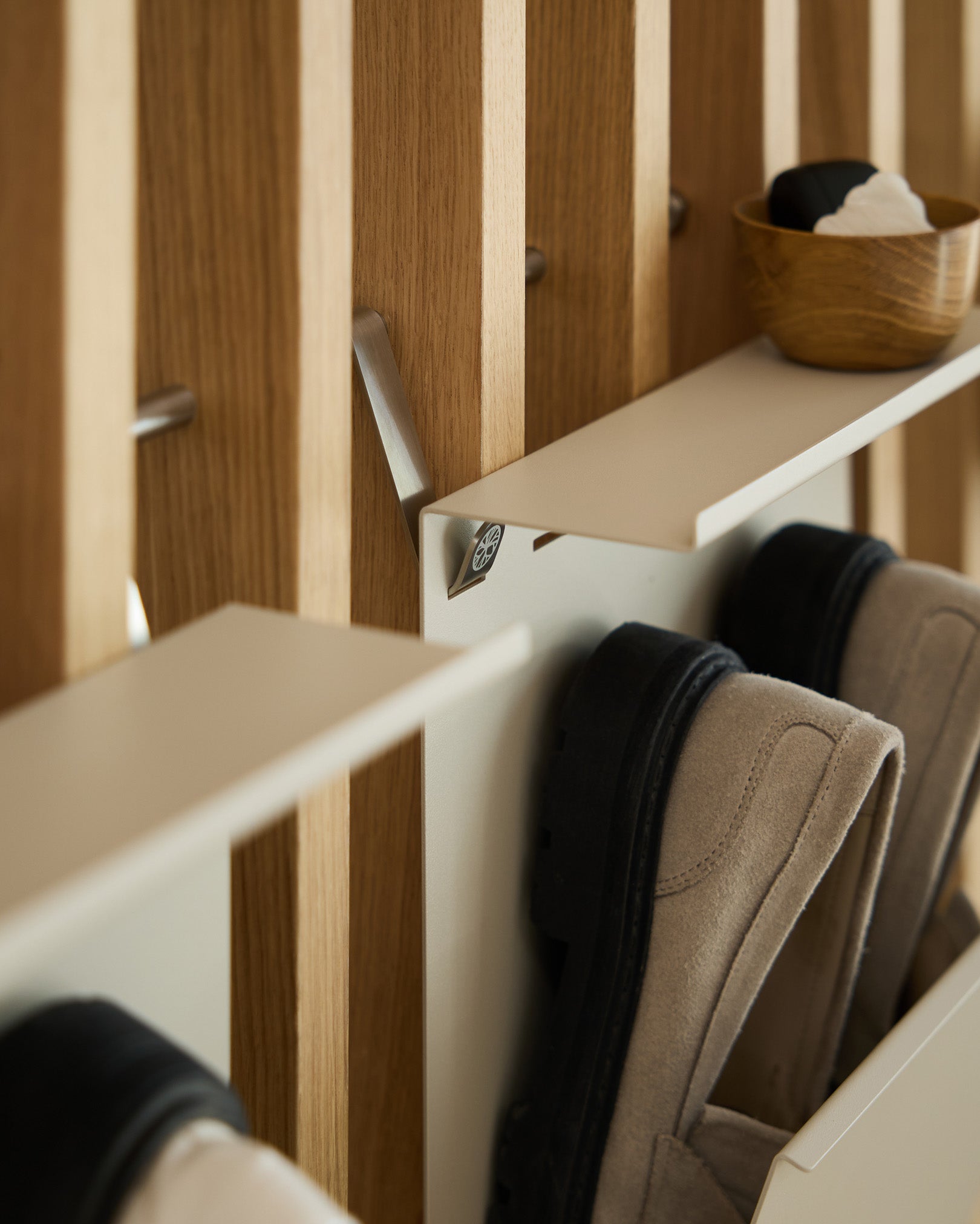 Portascarpe minimalista in steel verniciato a polvere beige di WoodUpp montato su un pannello scanalato nordico Pannello acustico, con una ciotola small per le chiavi appoggiata sopra.