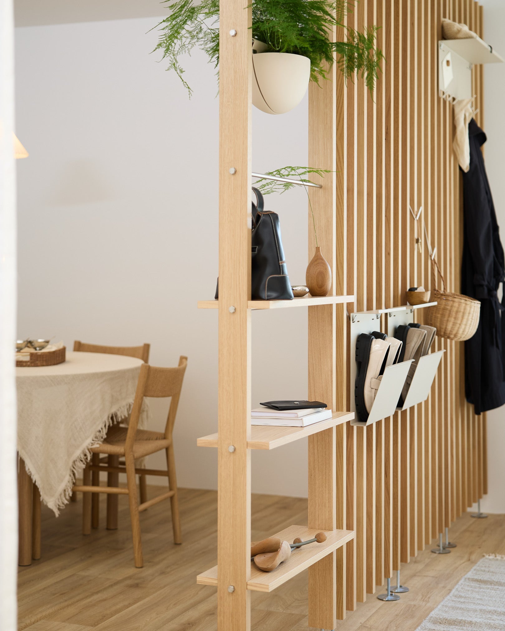 Una scaffalatura aperta in legno divide la zona pranzo e ospita Nell Shoe Storage in beige di WoodUpp, per uno spazio ordinato dedicato alle scarpe in una moderna casa nordica.