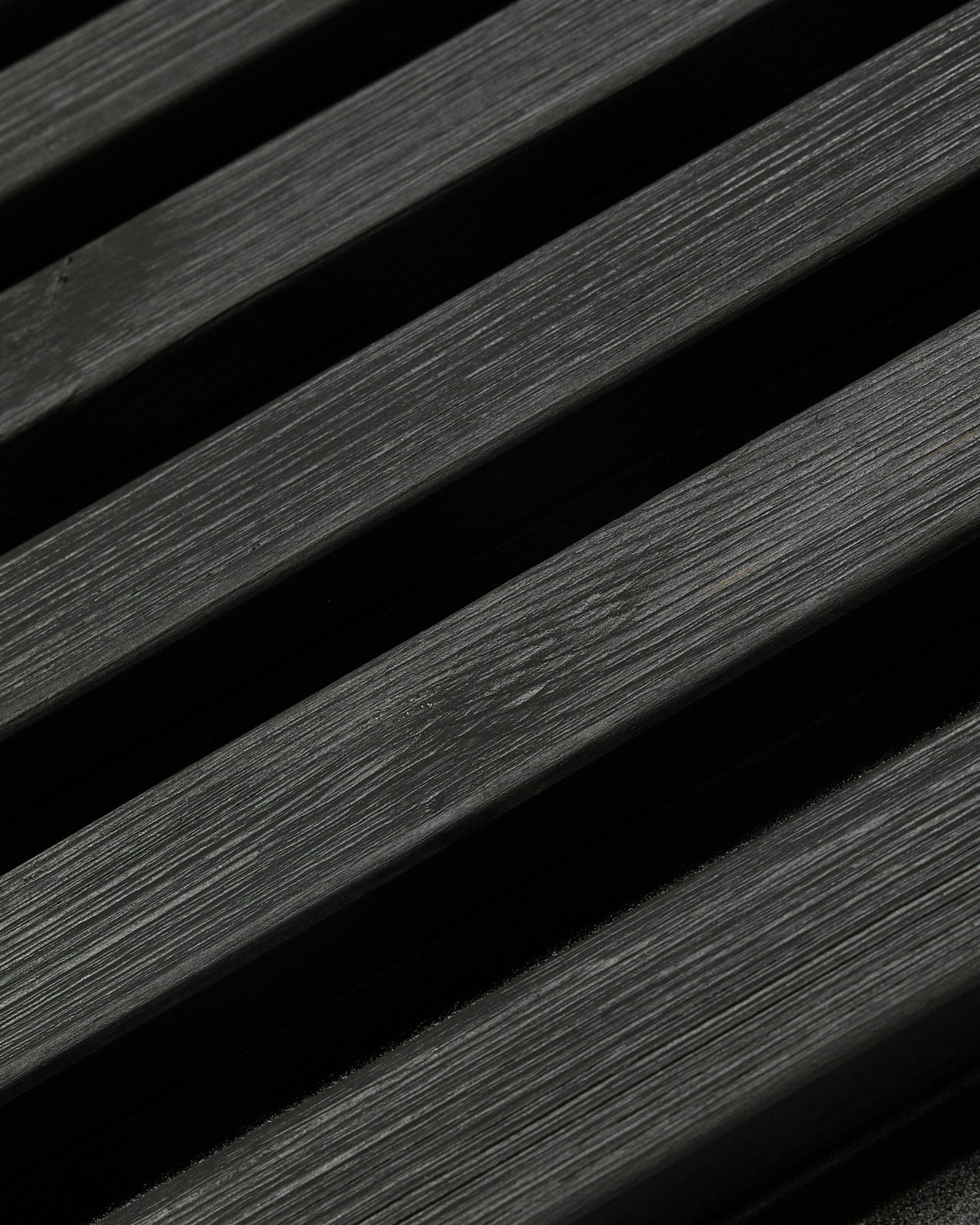 Pannello per facciata outdoor Aluwood di WoodUpp, Thermowood con finitura black, 240 x 45,1 cm, con doghe diagonali in abete nordico dalle venature visibili e giochi di ombra.
