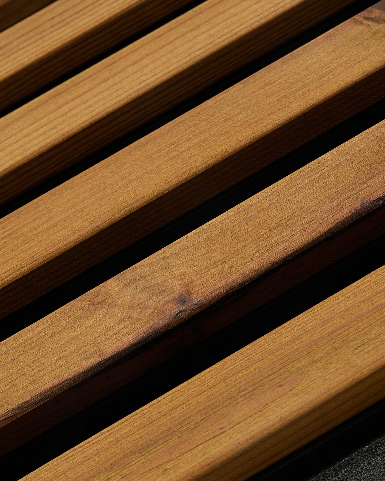 Primo piano del pannello per facciata WoodUpp Aluwood in brown oliato (240 x 45,1 cm), in abete nordico termotrattato, ripreso in angolazione per mostrare le doghe con spazi scuri tra l’una e l’altra.