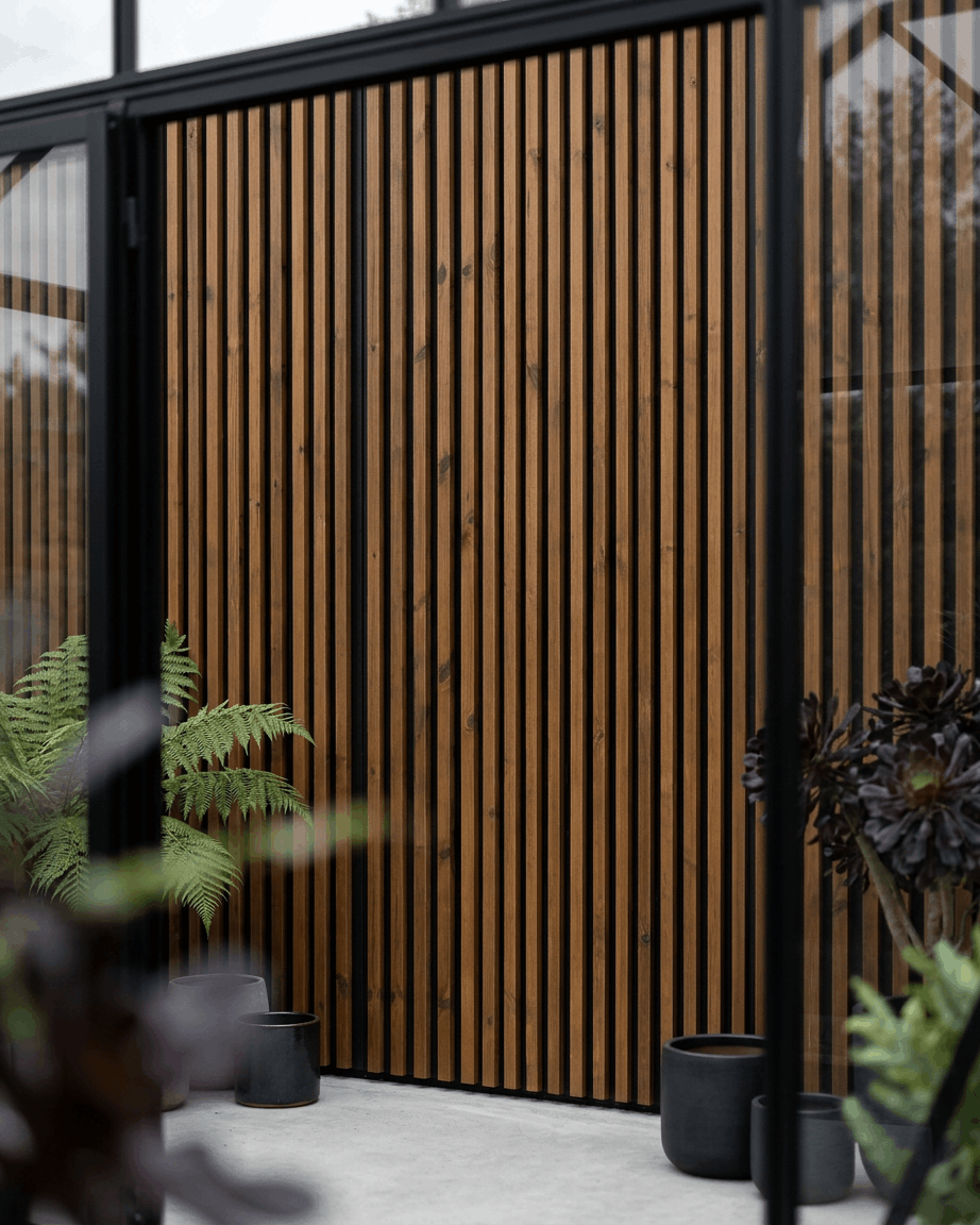 Pannello di facciata per esterni WoodUpp Aluwood in brown oliato abbinato a fioriere black e piante verdi, per creare un patio nordico minimalista.