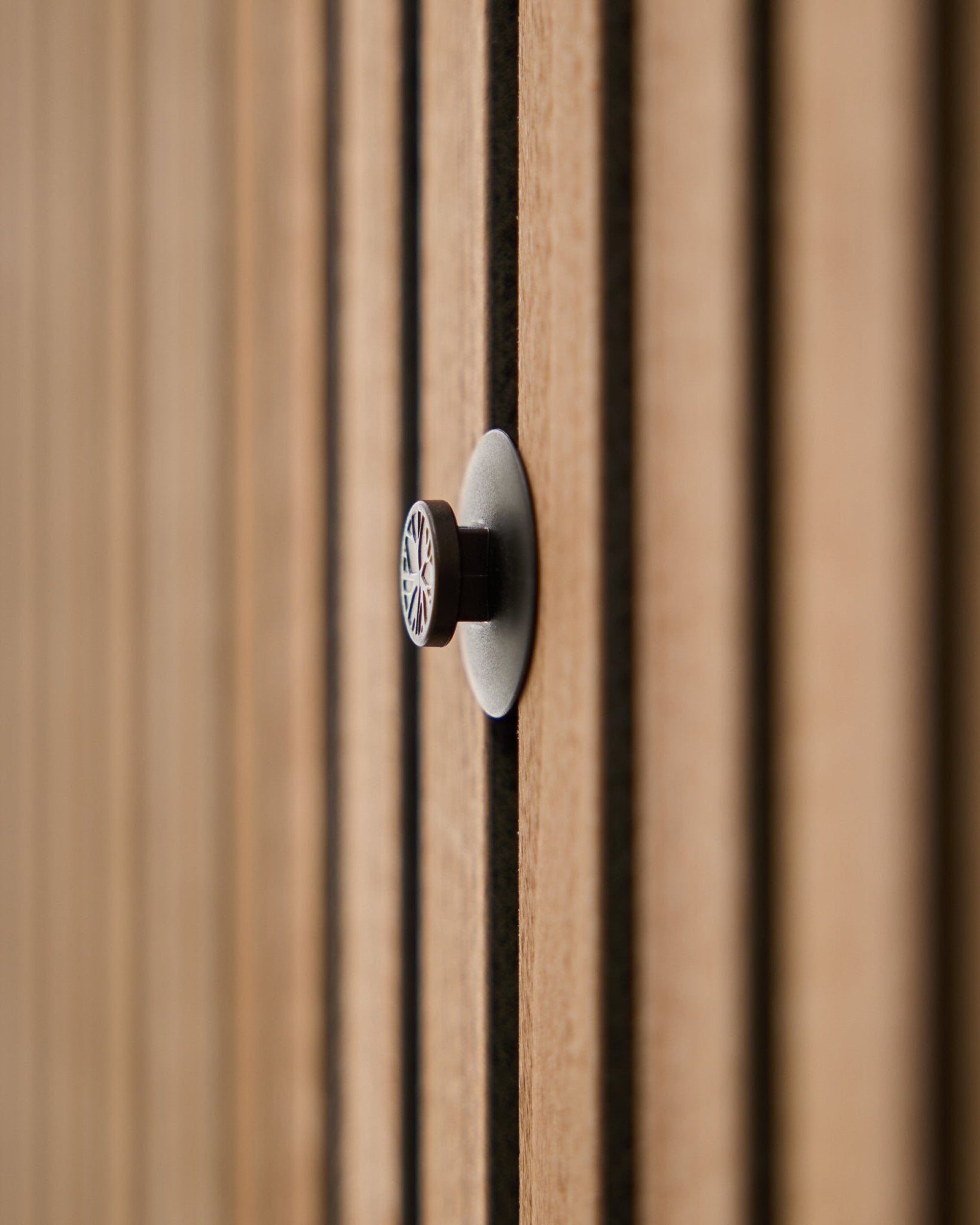 Primo piano di un set di Dupps | Light knob (3 pomelli più utensile) di WoodUpp installato su un pannello acustico a doghe, con le doghe in legno leggermente sfocate sullo sfondo.