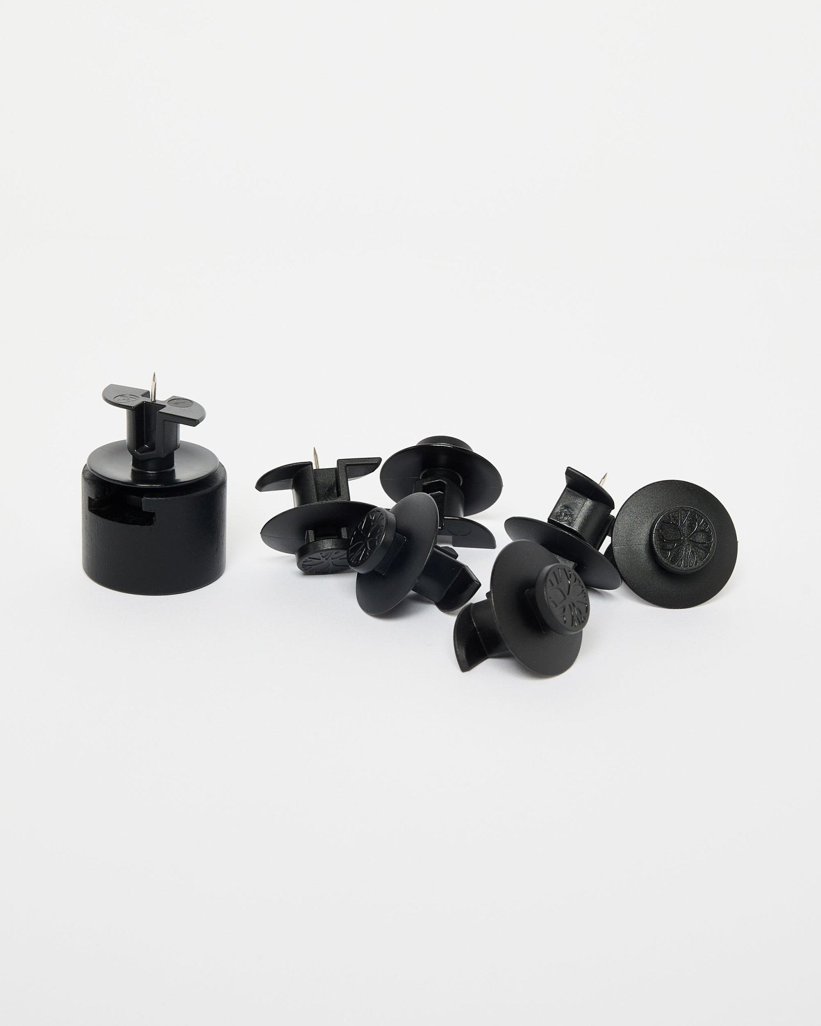 Dupps di WoodUpp: sette sigilli di sicurezza in plastica black, uno strumento di installazione e staffe in nylon disposti su uno sfondo bianco uniforme.
