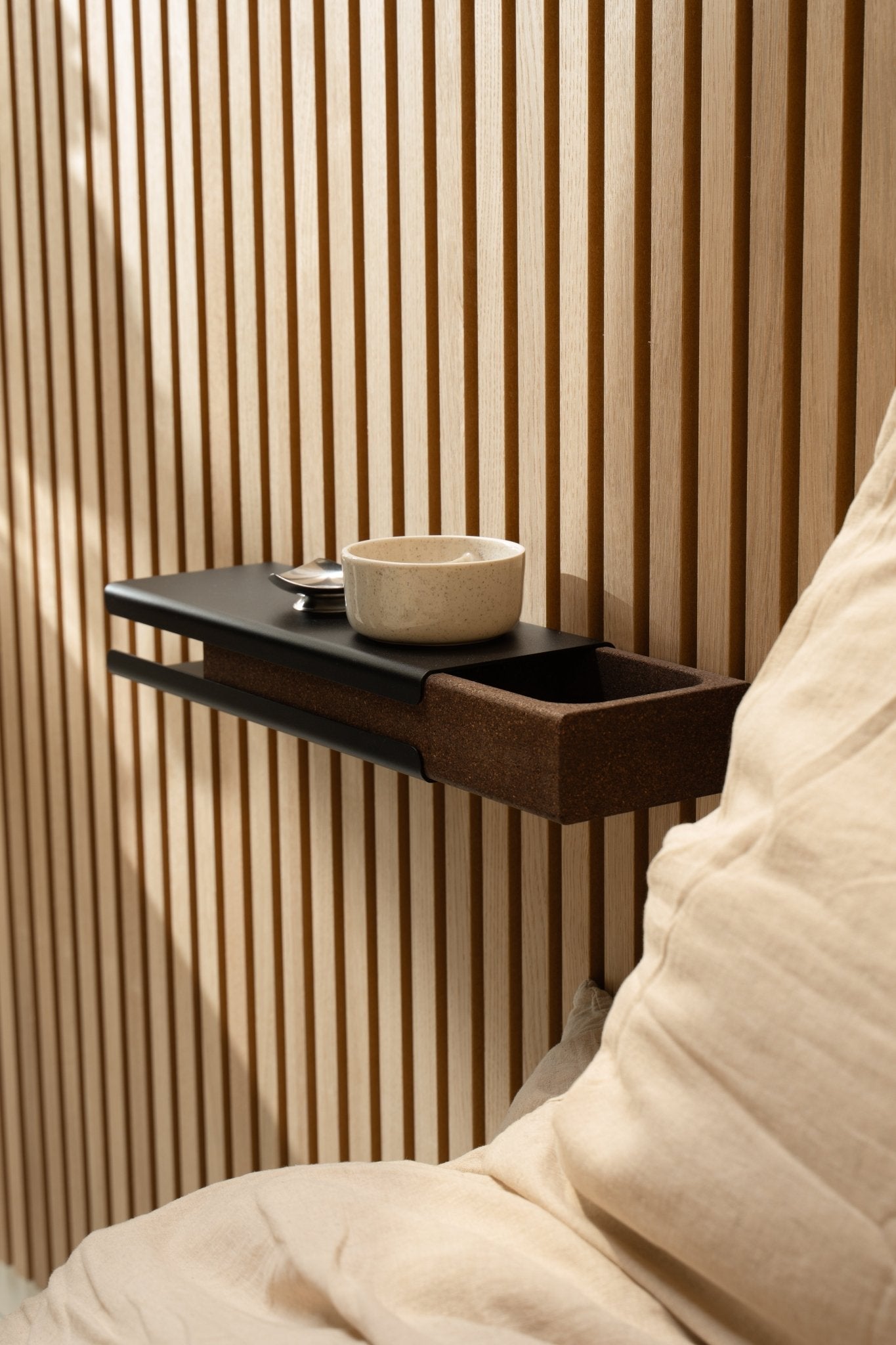 Mensola da parete minimalista con una ciotola in ceramica e WoodUpp Norr Key Tray accanto a un cuscino beige e a Akupanel Pannello acustico, illuminata da una morbida luce naturale.
