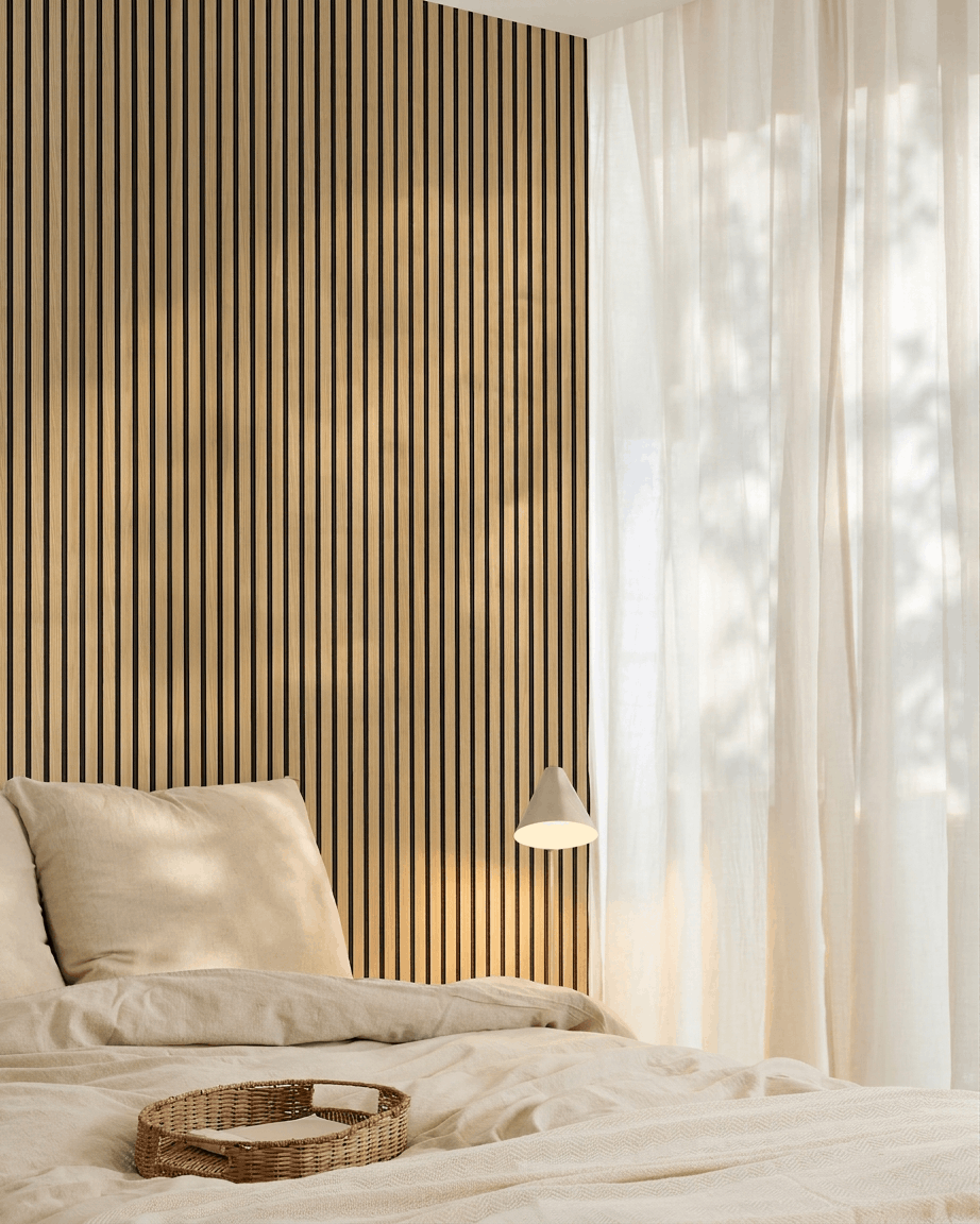 Camera da letto minimalista con biancheria da letto beige, una parete d’accento WoodUpp Akupanel Southern Rovere Pannello acustico, un vassoio intrecciato sul letto e tende velate che lasciano entrare la luce naturale.