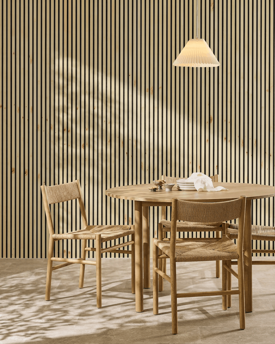 Il pannello acustico WoodUpp Akupanel, disponibile in legno naturale, alp e feltro nero, conferisce un tocco nordico caldo e minimalista a una zona pranzo in stile scandinavo con tavolo e sedie.