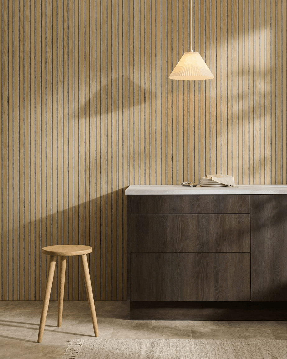 Interno nordico minimalista con un Akupanel Pannello acustico WoodUpp in Classic Rovere con feltro Grey, abbinato a uno sgabello in legno, un mobile scuro e un piano di lavoro bianco.