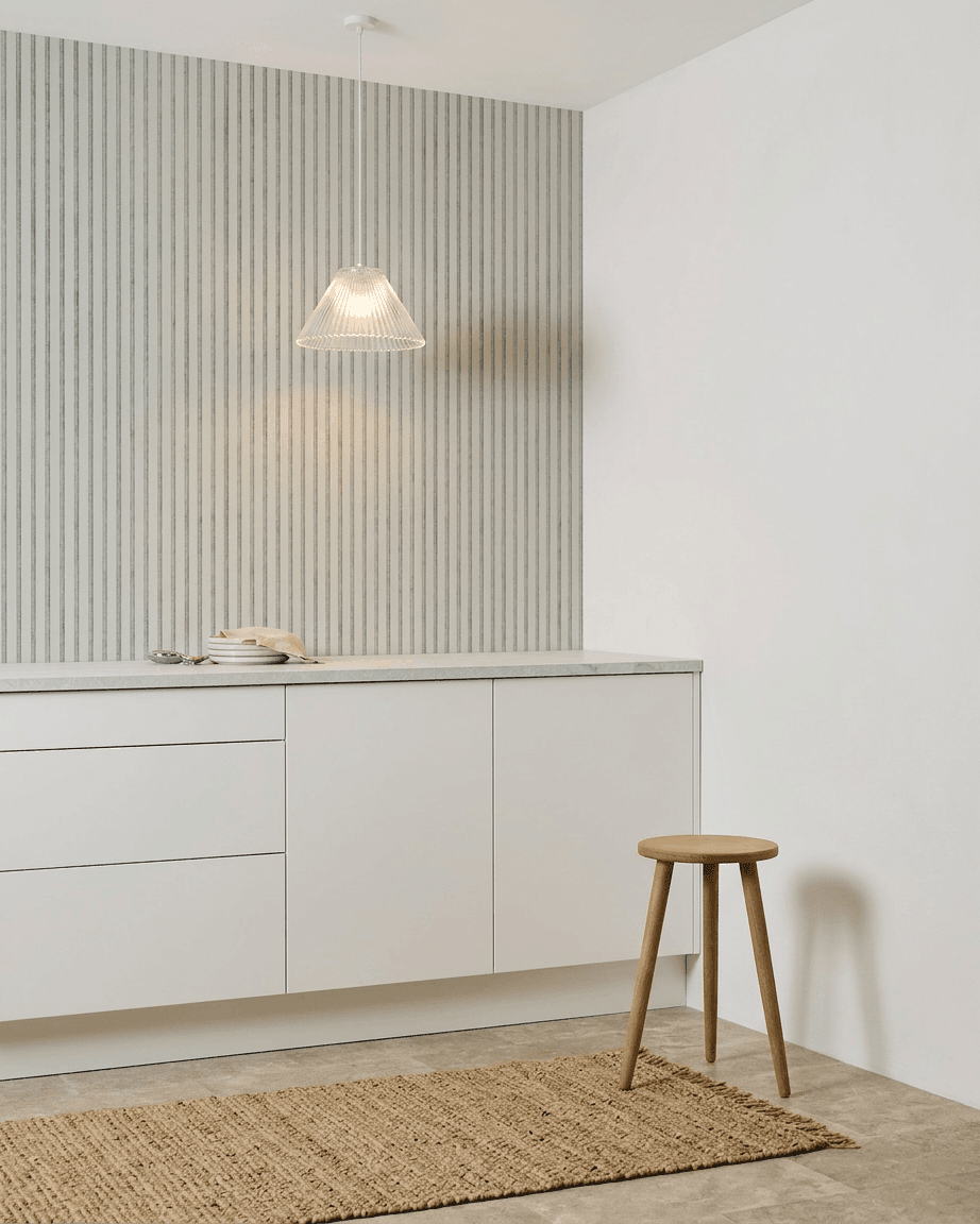 Cucina minimalista con mobili bianchi, uno sgabello in legno, un tappeto intrecciato e un WoodUpp Akupanel Snow Pannello acustico installato per l'assorbimento acustico.