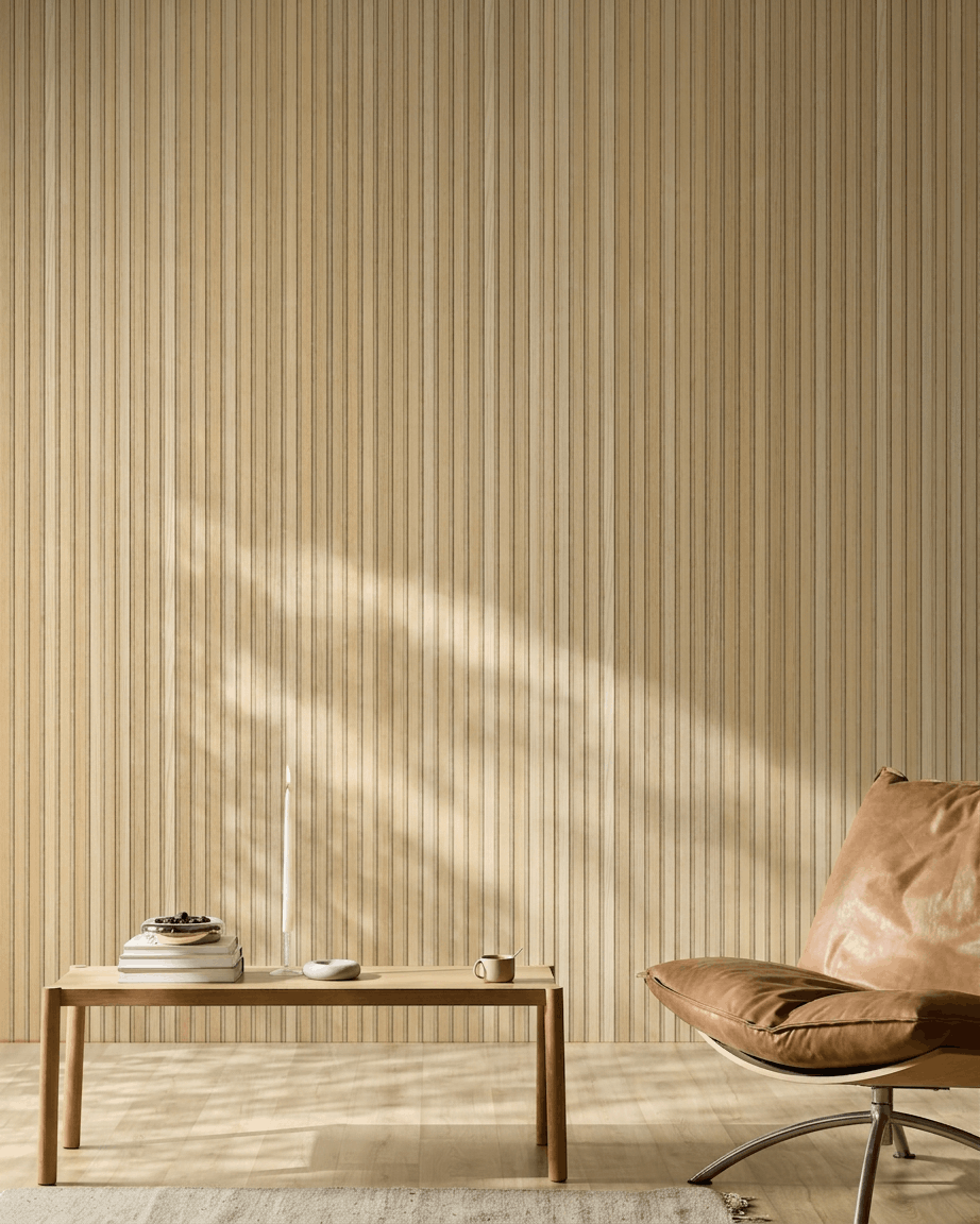 Interno scandinavo minimalista ambiente con un pannello acustico in legno WoodUpp Akupanel in Natural Wood Classic Rovere, sedia in pelle color cuoio e semplice tavolo in legno con dettagli accoglienti.