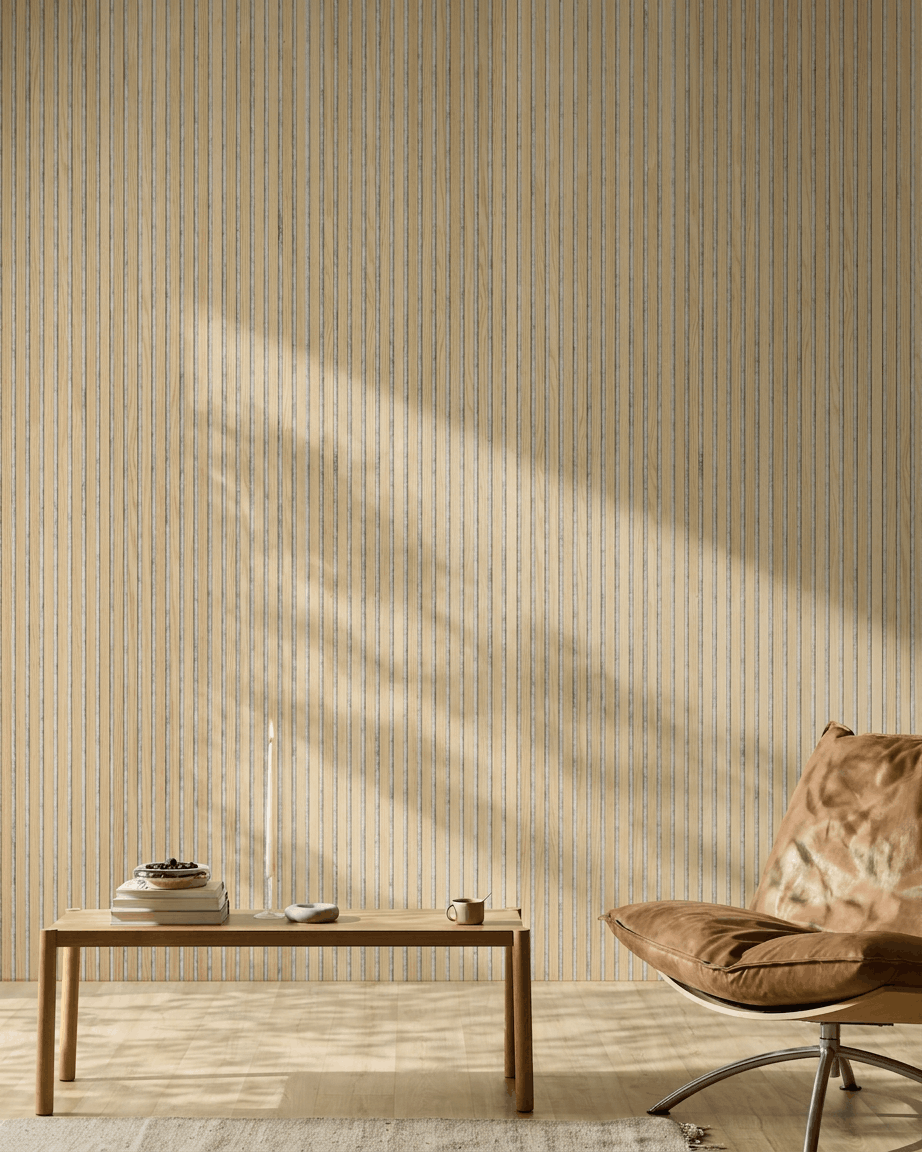 Interno minimalista con ambiente, una poltrona in pelle color cuoio, un tavolo in legno e una candela. Il pannello fonoassorbente a doghe WoodUpp Akupanel Classic Rovere aggiunge stile nordico e comfort acustico.