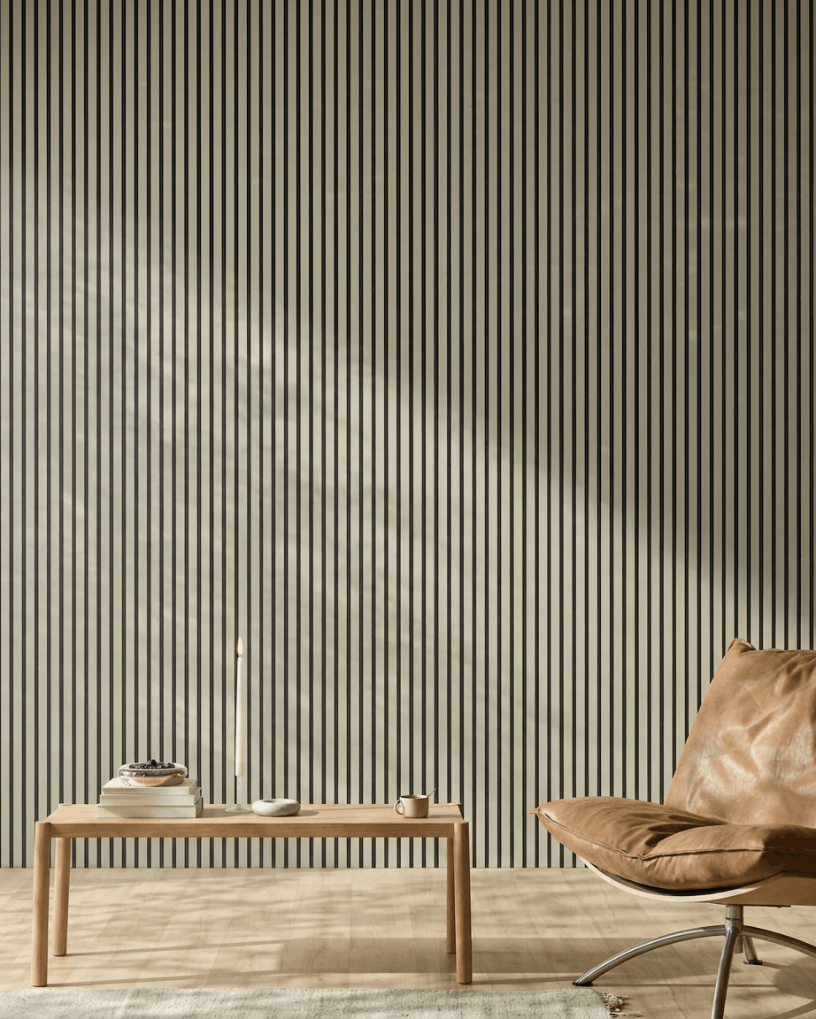 Interno minimalista ambiente con una poltrona in pelle color cuoio, una panca in legno, libri, una candela e il Akupanel Stone/Black Felt Pannello acustico di WoodUpp (240x60 cm) sulla parete.