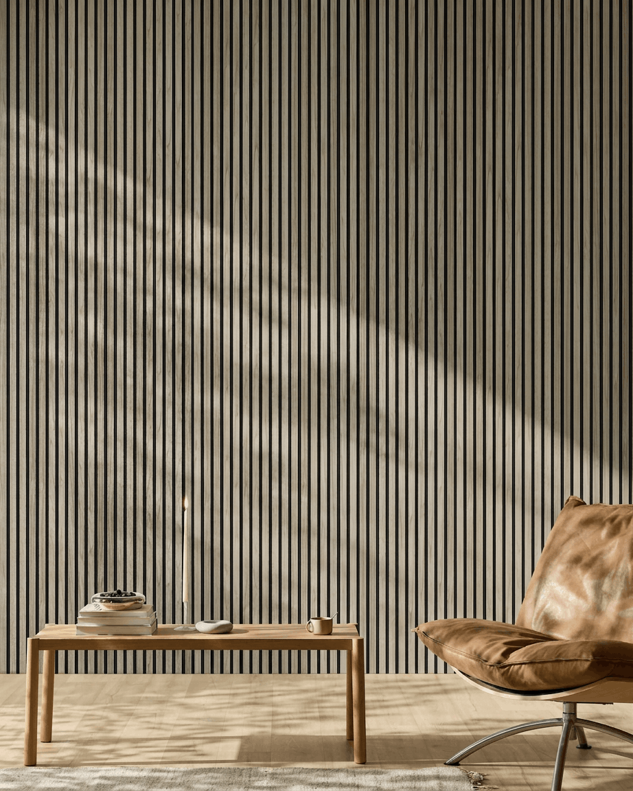 Ambiente ambiente minimalista con un WoodUpp Akupanel 240x60 cm in Weathered Rovere con feltro black, panca in legno, libri, candela, tazza e poltrona in pelle color cuoio.