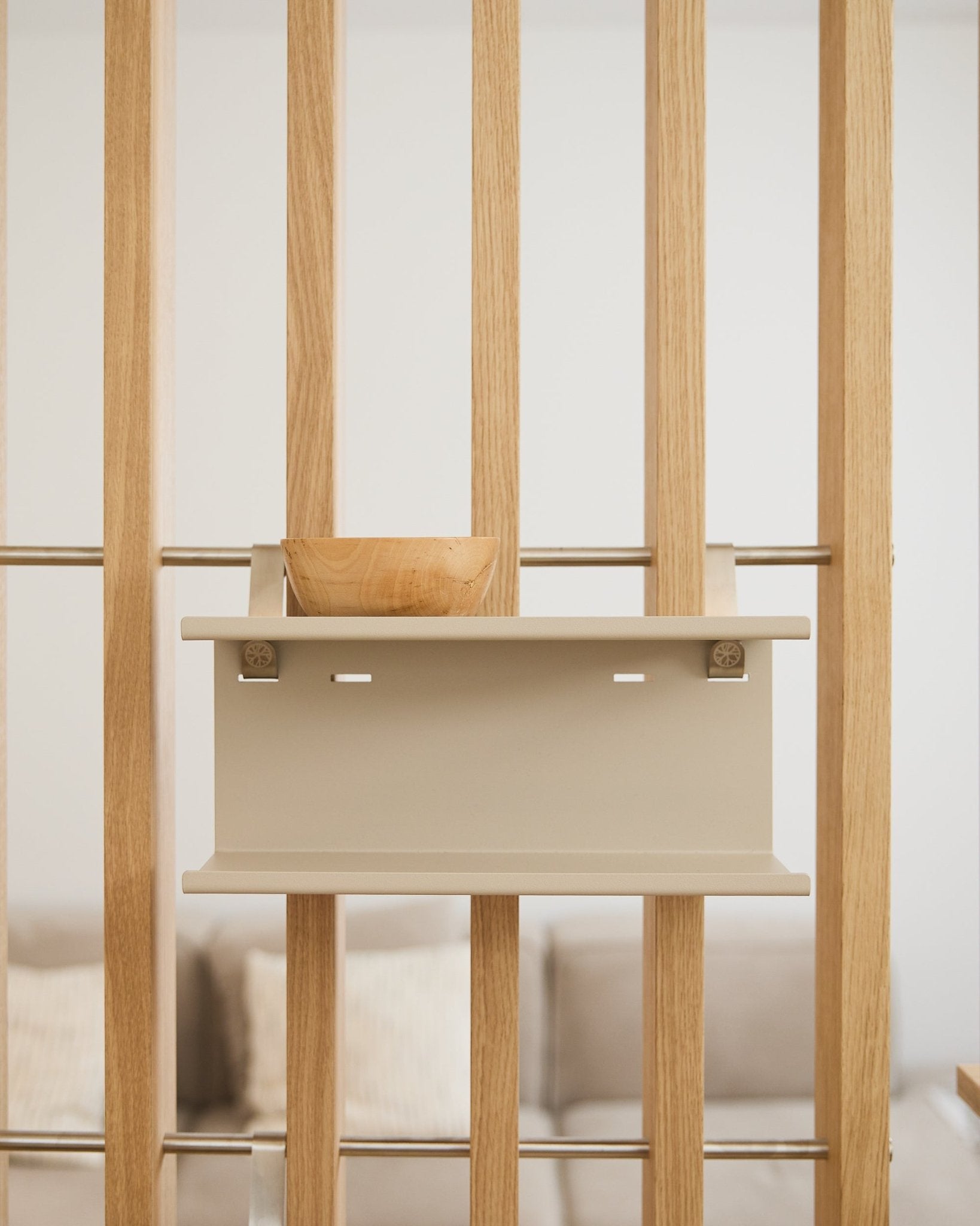 Una ciotola in legno small sulla beige Nell Double Metal Shelf di WoodUpp (31,7 cm), con un divano e dei cuscini sfocati sullo sfondo.